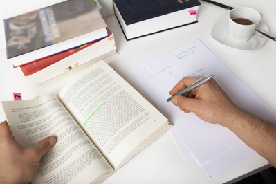 man reading book and taking notes