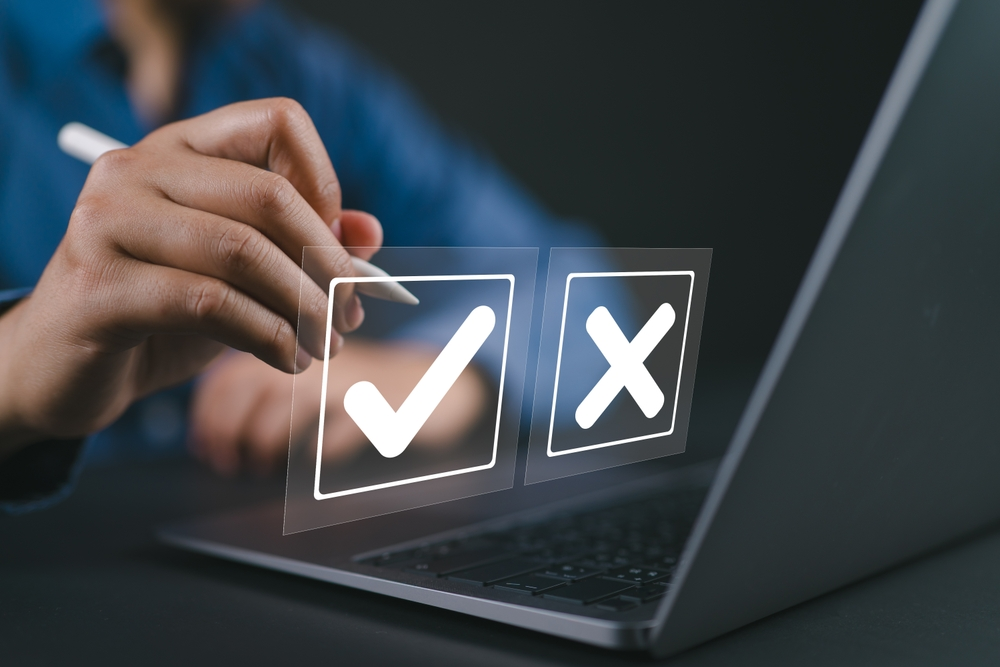 person sitting at laptop making choice between right and wrong shown by checkmark and X