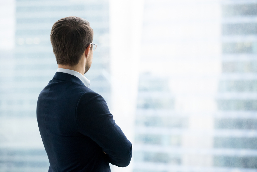 businessman looking out window at cityscape 